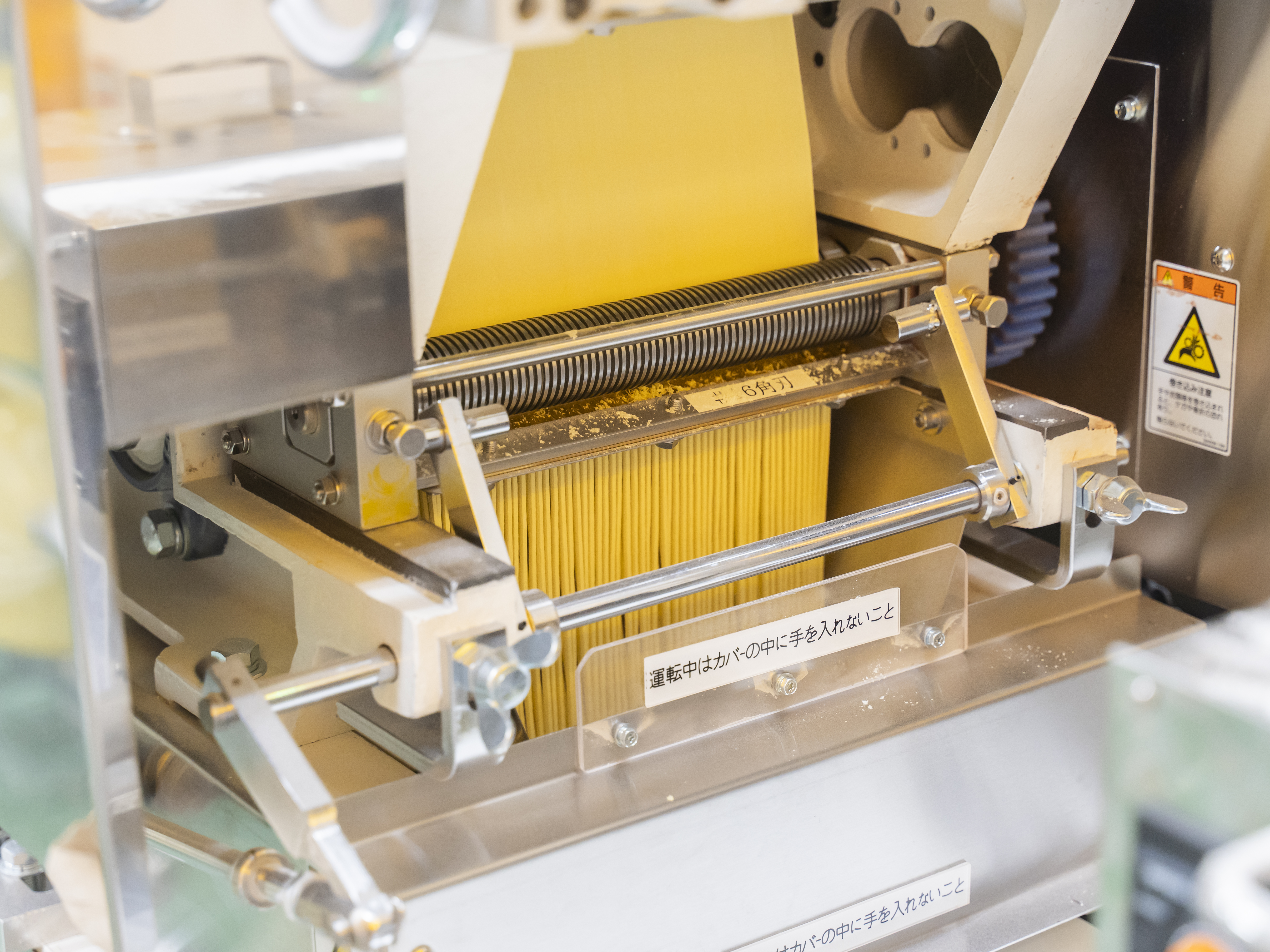 【基本的な製麺工程⑧】麺帯をみなさんがいつも見る麺の形にカットします。小麦粉から麺になるまでの一連のすべての工程に携わるので、自分がつくった！という自負とやりがいを感じられます。