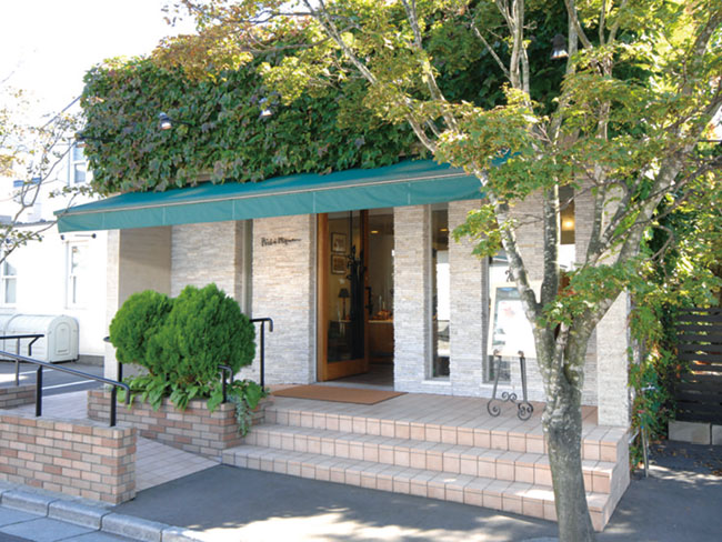 閑静な住宅街にひっそりと佇む、深い緑に囲まれたフランス菓子店がペシェ・ミニョンです。店内は温かみのあるインテリア、そして奥には暖炉。ゆったりと風の音をききながら、新鮮なケーキを楽しめる空間です。