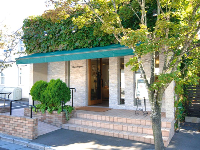 閑静な住宅街にひっそりと佇む、深い緑に囲まれたフランス菓子店がペシェ・ミニョンです。店内は温かみのあるインテリア、そして奥には暖炉。ゆったりと風の音をききながら、新鮮なケーキを楽しめる空間です。