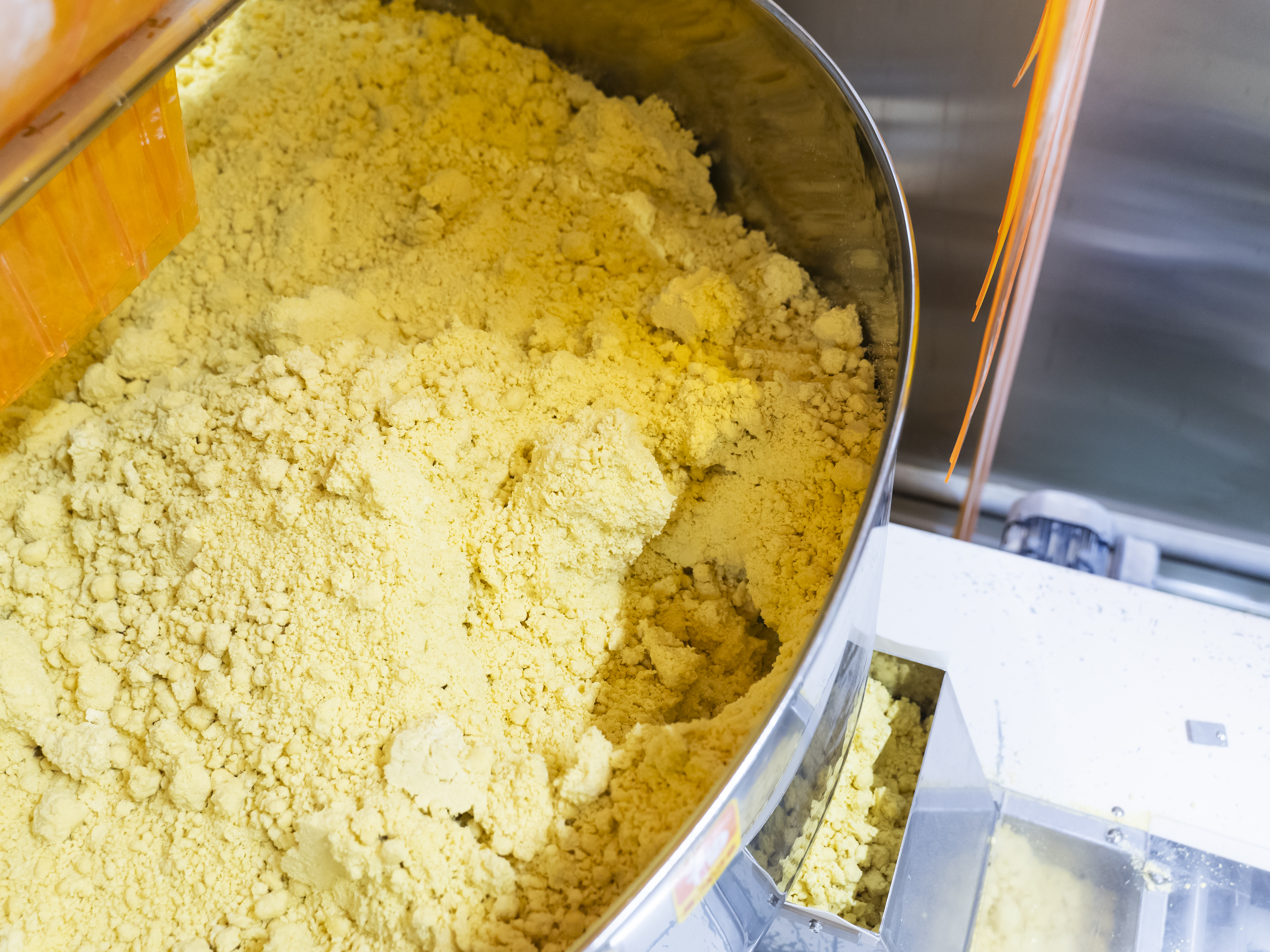 【基本的な製麺工程④】投入された原料をミキサーで撹拌（混ぜ合わせ）します。小麦粉や水などの原材料を適切な比率でミキサーに投入することが重要で、そこは機械ではなく人の手で行います。