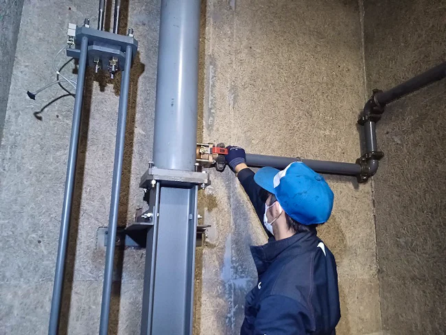 油圧エレベーター用配管の点検作業です。ボルトの緩み、油漏れが無いかをチェックしています。入社1年目から行う業務です。