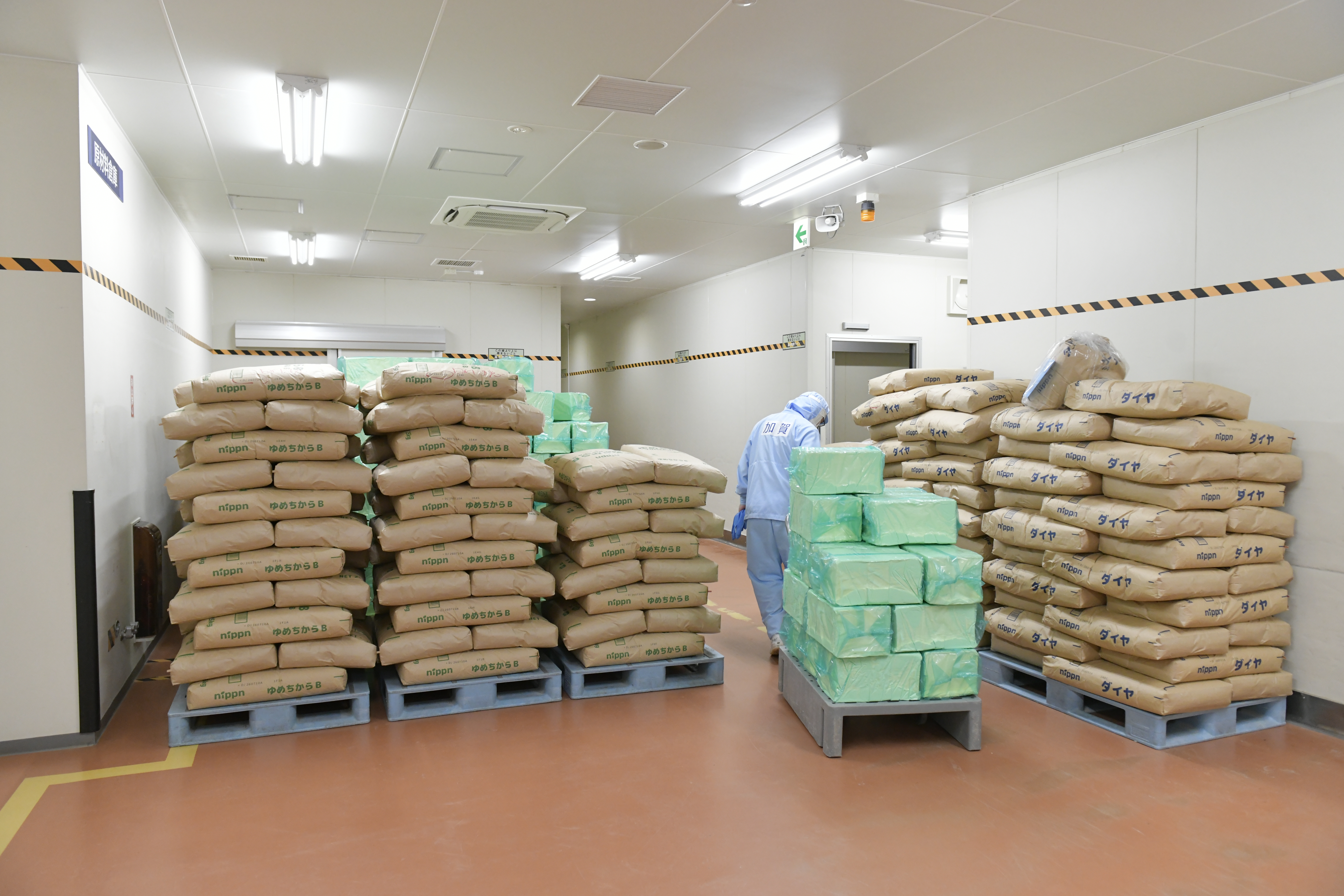 【作業行程をフカボリ③】ラインが稼働する前には、原材料が置いてある倉庫から使用する分の小麦やマーガリンなどを運び出します。
ハンドリフトを使うので荷台に原材料を載せた後は、引っ張りながら運びます。