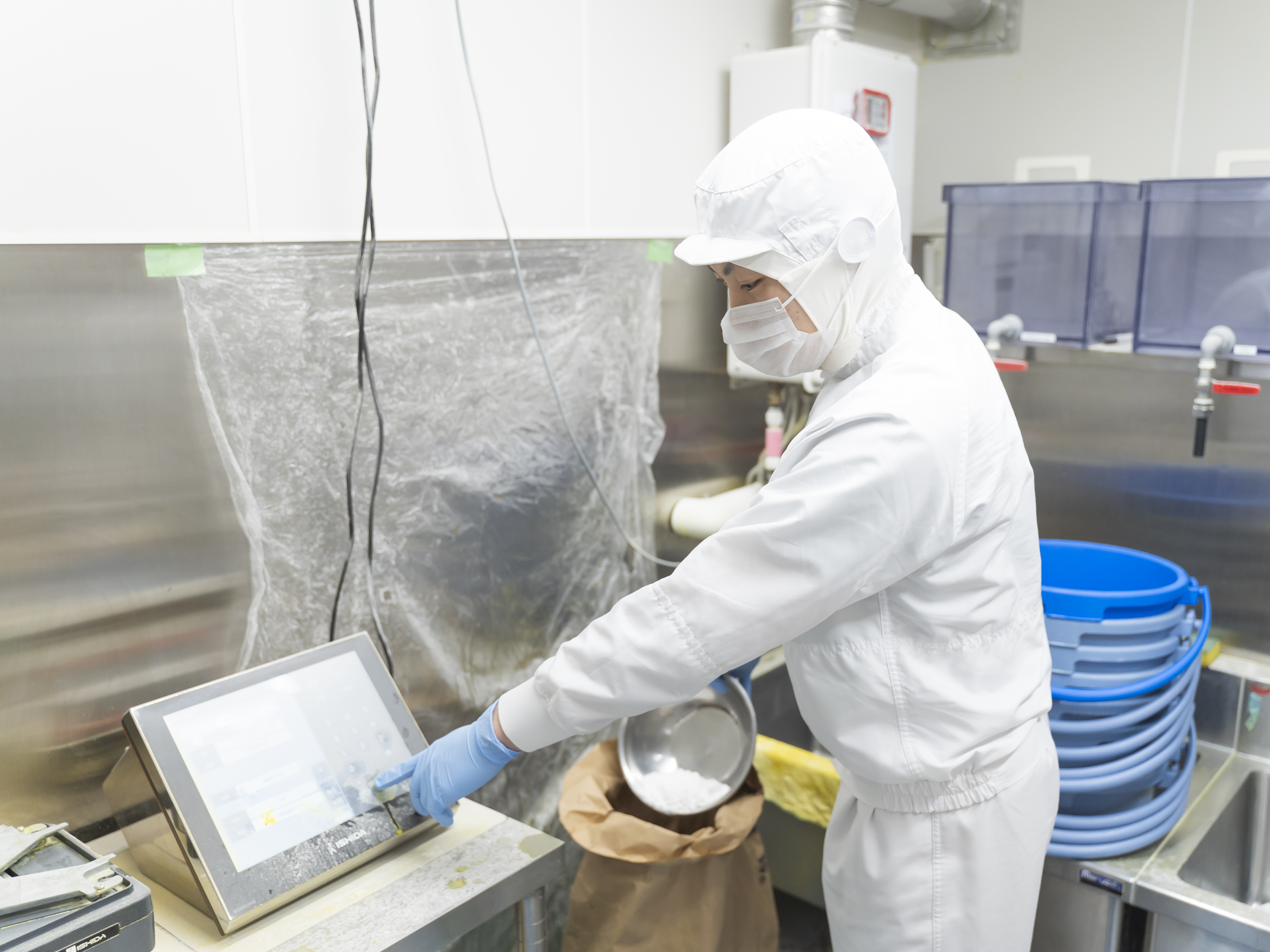 【基本的な製麺工程①】　麺の主原料となる小麦粉をレシピに沿って計量します。単純な作業のように思われるかもしれませんが、実は奥が深く、食文化を支えるという大きなやりがいのある仕事です。