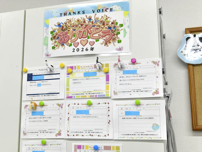 【「サンクスボイス」で意欲UP!】壁一面に広がるのはお客様からの感謝の言葉。アンケートの「助かりました」や感謝のお電話など、「誰かの役に立てた」実感を全員で共有。この温かい声が、自信に繋がっています。