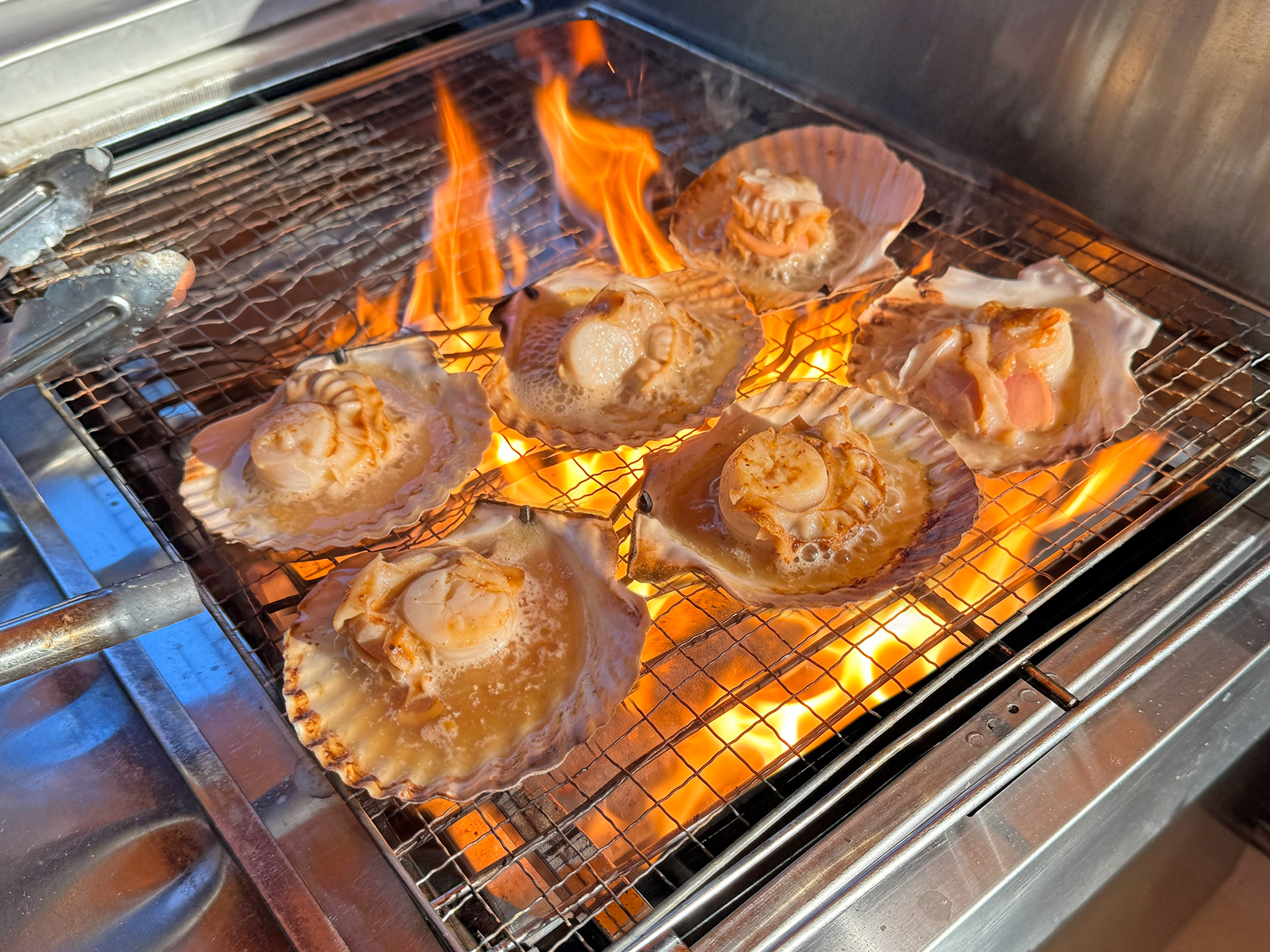 【店頭の活ほたて貝をその場で豪快に貝焼きに！朝市ならではの光景です。】