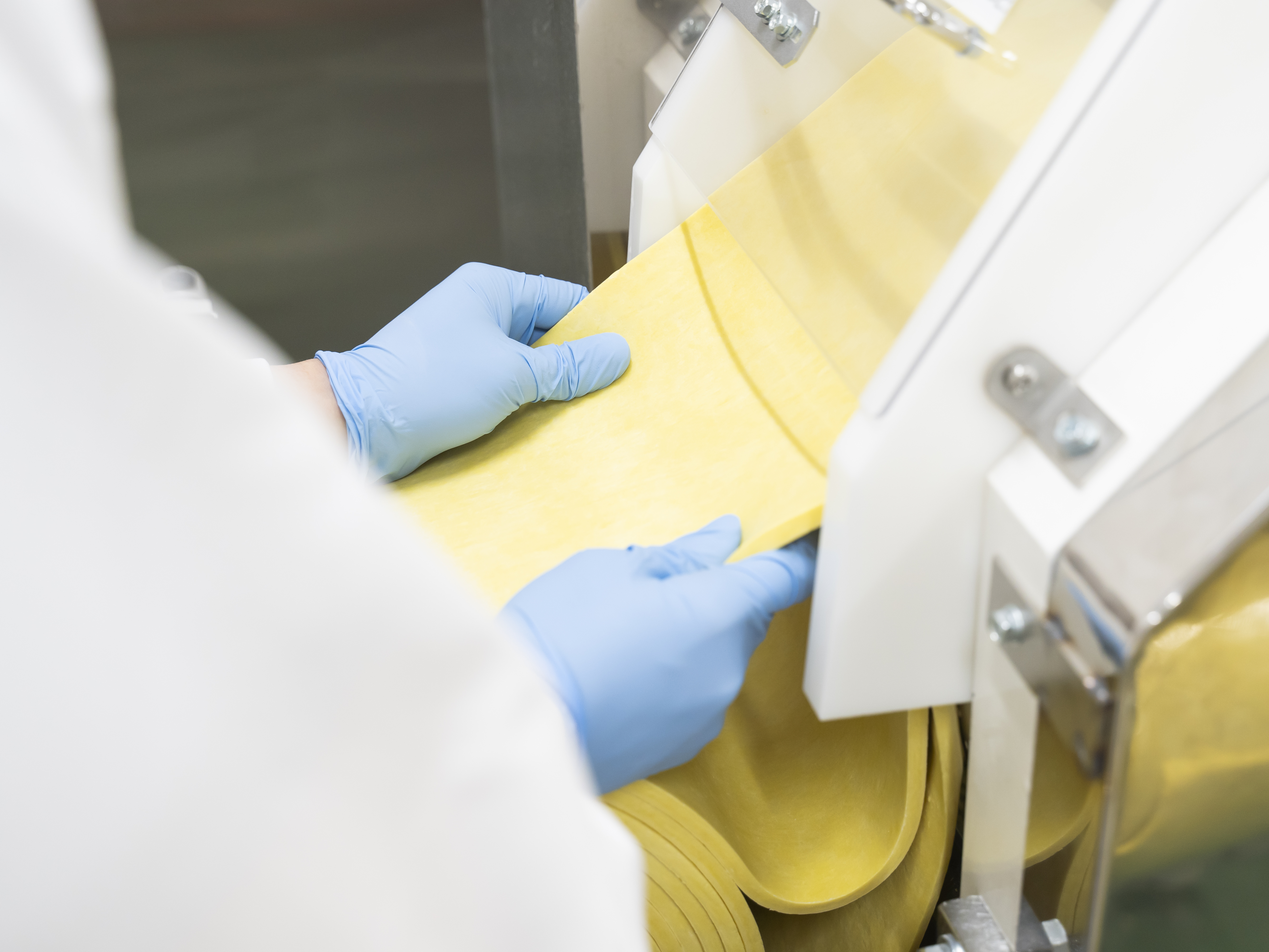 【基本的な製麺工程⑥】帯状にした麺生地に圧力をかけながら伸ばすことで、コシのある麺をつくることができます。人気店の多様な種類の麺をつくる当社での仕事は、麺に関する知識を奥深く学ぶことができる環境です。