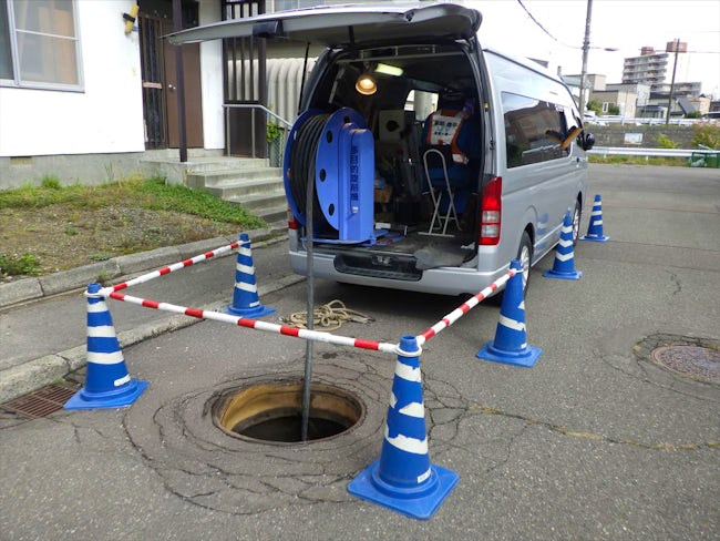 機械を上からマンホールに通していく人、マンホールの下に降りて機械を受け取る人、カメラを操作する人など、チーム内で業務を分担しながら進めていきます。