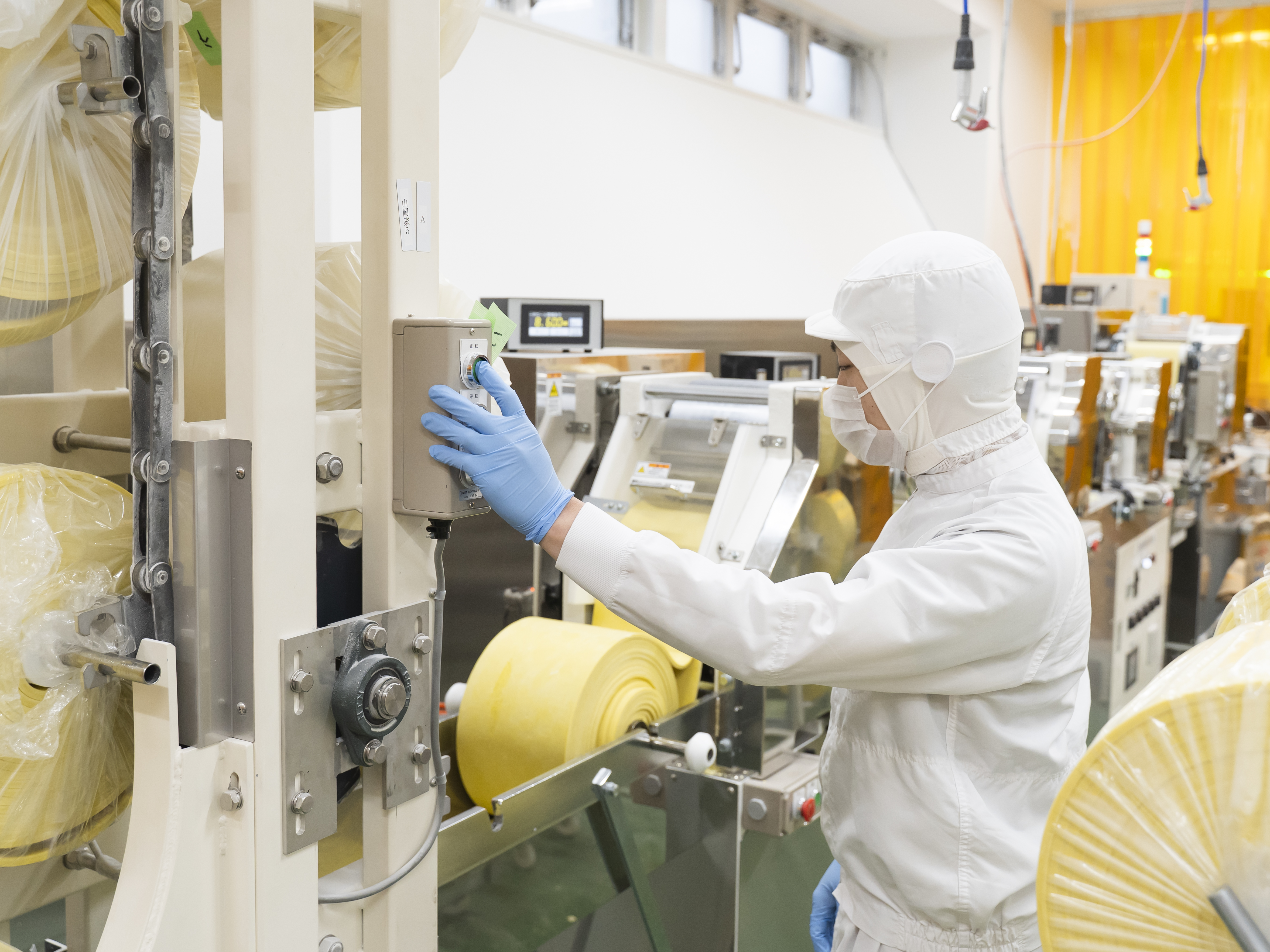 【基本的な製麺工程⑦】麺生地を機械にセットする際に、人の目や触った感じで状態を確認します。生地のコシや弾力などについては感覚的な部分が大きく、経験を通して感覚を養っていきます。